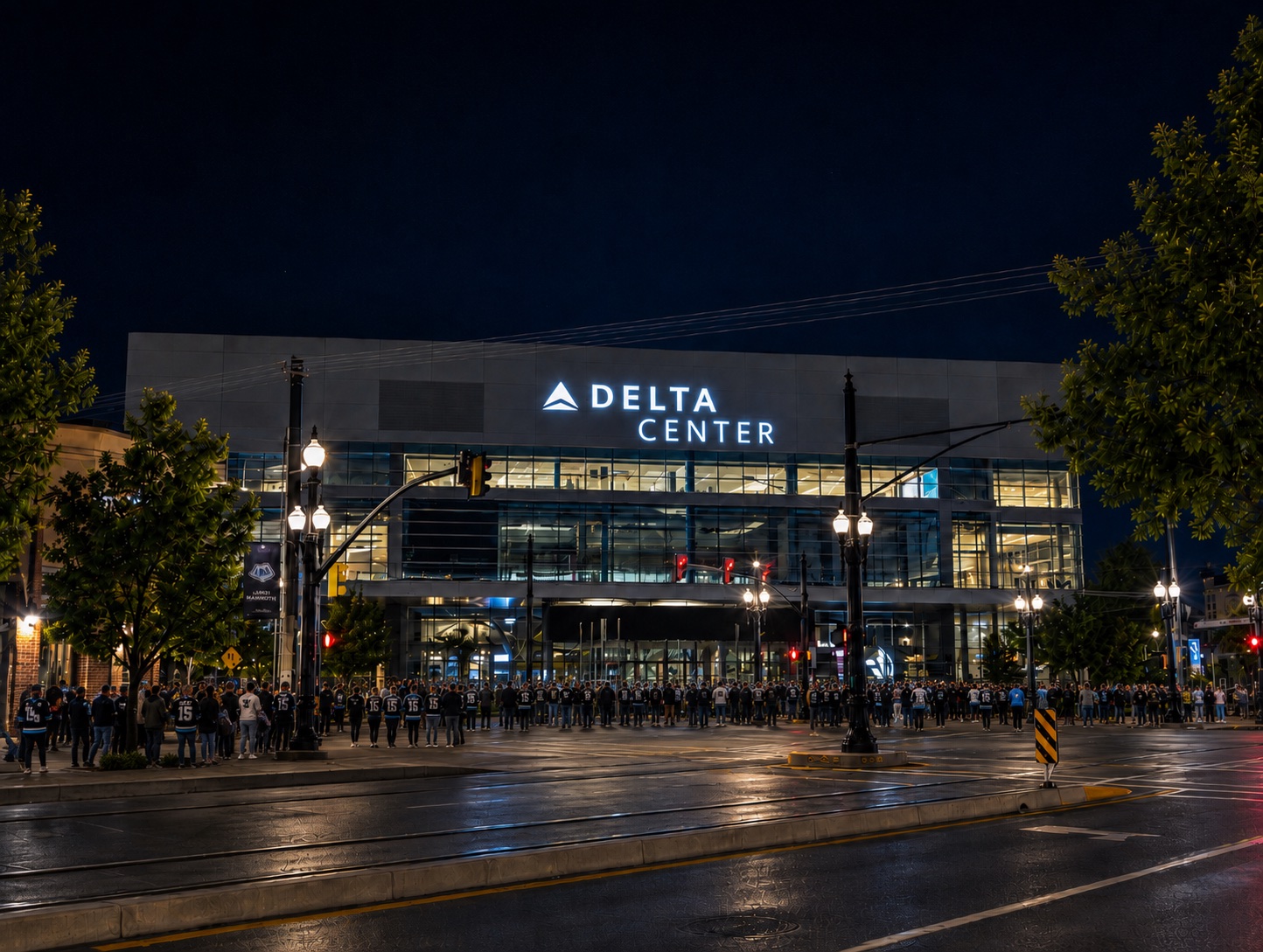 Fans gathering outside Delta Center before a Utah hockey game at night.